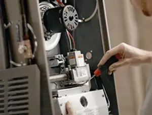 Furnace repair technician inspecting internal components and wiring in Reading, MA
