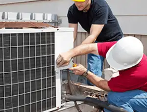 HVAC technicians repairing an outdoor AC unit on a rooftop in Reading, MA